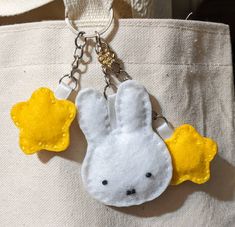 a white and yellow bunny keychain hanging from a tote bag