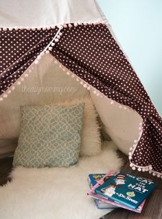 a teepee with some books on the floor and a pillow in front of it