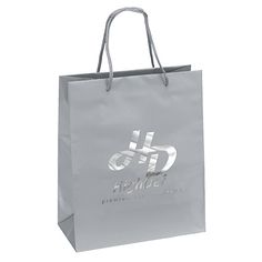 a grey shopping bag with the logo on it and silver handles, in front of a white background