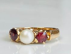 "Garnet ring; late 1800s Victorian era stunning red garnet ring with two cushion cut garnet stones with beautiful rich depth of color claw set in 14K gold setting and in a romantic three stone setting with lovely central pearl. The pearl has lovely glossy nacre and makes a nice contrast with the deep red hues of the garnets. What a striking and unusual engagement ring this would make! The three stones form a \"Past, Present, Future\" setting. The setting and stones are in nice condition. Ring is Red Pearl Ring, Antique Three Stone Ruby Ring For Formal Occasions, Victorian Style Three Stone Ruby Ring As Gift, Ruby And Pearl Ring, Engagement Ring Three Stone, Unusual Engagement Rings, Garnet Engagement Ring, Ring Three Stone, Red Garnet Ring