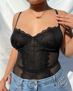 a woman in jeans and a black top is holding her hand up to her chest