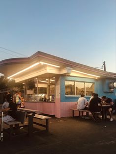 people are sitting at picnic tables in front of a food truck that is pink and blue