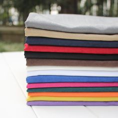 a stack of folded shirts sitting on top of a white table next to each other