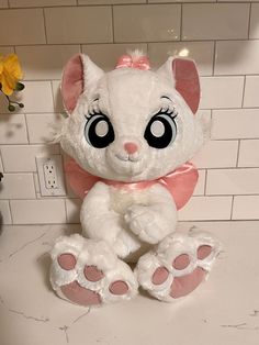 a white stuffed animal sitting on top of a counter next to a flower pot and tile wall