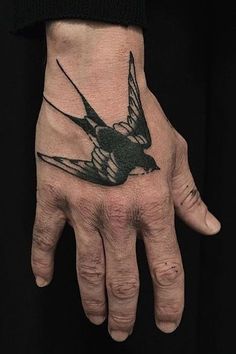 a person's hand with a bird tattoo on it