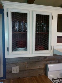 a kitchen cabinet with two glass doors on the top and bottom, next to a sink