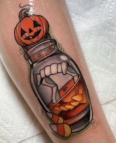 a person with a tattoo on their leg that has a pumpkin in a glass jar