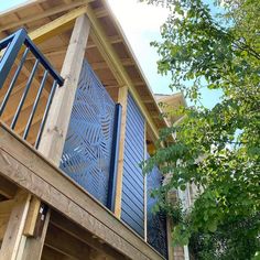 a wooden house with blue shutters on the balcony