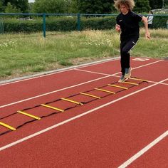 a young man is running on a track with ladders in the middle of it