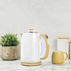 a white and yellow coffee pot sitting on top of a counter next to a cup