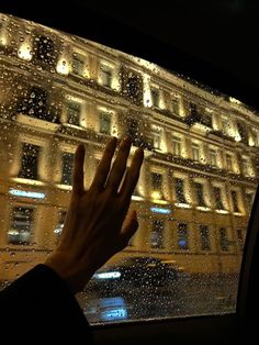 a person's hand is seen through the window of a car at night time