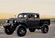 an old black truck is parked in the desert