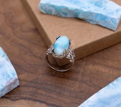 Celebrate timeless romance with our Vintage-Style Silver Ring, a masterpiece meticulously handcrafted by Gemoholic Jewelry. This enchanting ring features a central oval Larimar gemstone, elegantly embraced by two delicately crafted hearts on each side. The vintage-inspired design captures the essence of love's enduring beauty, making it a symbol of affection and timeless elegance. Oval Larimar Centerpiece: At the heart of this ring gleams a central oval Larimar gemstone, celebrated for its soothing blue hues and exceptional quality. Larimar is known for its energetic qualities, promoting tranquility, reducing stress, and nurturing inner peace. Dual Heart Accents: On each side of the Larimar centerstone, two gracefully sculpted hearts add a touch of vintage romance to the design. These hear Oval Moonstone Larimar Ring, Elegant Turquoise Larimar Ring As Gift, Blue Stones Jewelry, Ring Blue Stone, Larimar Ring, Larimar Rings, Vintage Romance, Meaningful Jewelry, Ring Blue