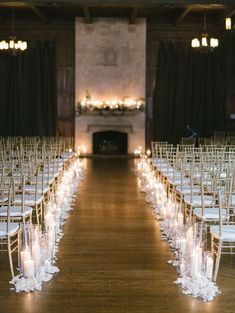 rows of white chairs with candles on them in front of a fire place and fireplace