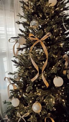 a decorated christmas tree with gold ribbon and ornaments