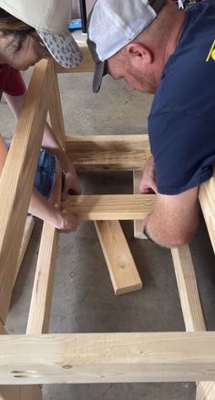 a man and woman working on wooden furniture