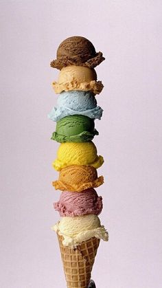 an ice cream cone filled with lots of different colored ice creams on top of each other