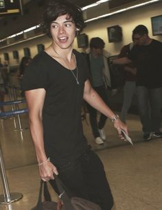 a young man is pulling his luggage through an airport terminal and smiling at the camera