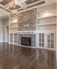 an empty living room with wood floors and stone fireplace