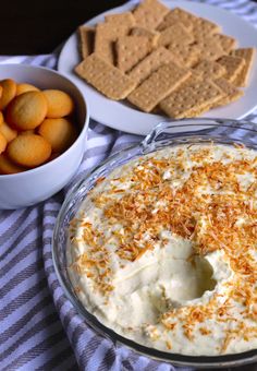 a bowl of crackers next to a plate of crackers on a striped table cloth