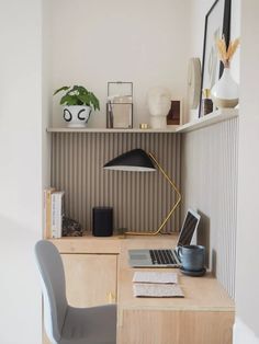 a laptop computer sitting on top of a wooden desk next to a lamp and chair