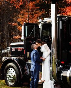 a bride and groom kissing in front of a semi truck with autumn foliage behind them