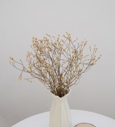 a white vase filled with lots of flowers on top of a table next to a slice of bread