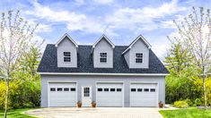 a two car garage with three windows on the top floor