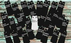 black and white aprons are laid out on a wooden table with the names of each individual