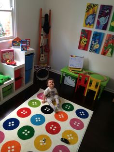 a baby sitting on top of a colorful rug in a child's play room