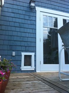 a chair sitting on top of a wooden deck next to a blue building with white doors