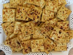 a white plate topped with lots of crackers on top of a doily covered table