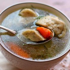 a spoon full of soup with dumplings and carrots