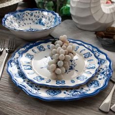 a table set with blue and white plates, silverware and utensils on it