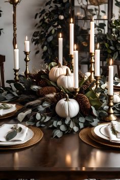 a dining room table set with white pumpkins, greenery and gold place settings