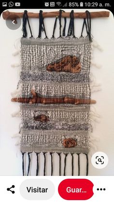 a wall hanging made out of different types of fabric and wood sticks with various designs on it