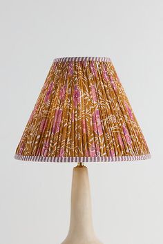 a lamp that is sitting on top of a wooden base with a pink and yellow shade