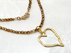 This classic and versatile light tortoiseshell glass beaded eyeglass loop necklace features a matte gold plated (nickel and lead-free) organic-shaped heart to hold your glasses.  It gives a clean updated look when you put the sidepiece of your glasses in vertically and fold.  The heart will hold almost all glasses. A matte goldplated bail holds the heart. The beads are 4mm fire-polished Czech light tortoiseshell glass for even size and shape. These beads, imported from the Czech Republic, are machine-faceted, then polished by glazing inside a red-hot oven. This gives them beautiful, glistening colors with a "softer" look and a smoother feel.  An eyeglasses holder can be a thoughtful gift for yourself or for a friend who wears reading glasses or sunglasses.  It prevents that annoying glasse Glasses Holder Necklace, Eyeglass Holder Necklace, Loop Necklace, Chain Sunglasses, Eyeglasses Holder, Necklace With Heart, Glasses Chains, Glasses Holder, Ring Chain