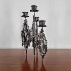 three metal candlesticks sitting on top of a wooden table