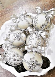 some white ornaments are on a plate with silver ribbons and bowknots around them