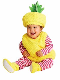 a baby wearing a yellow knitted pineapple hat and striped leggings sitting on the floor