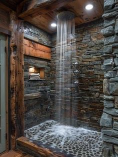 a shower head in the middle of a room with stone walls and flooring, surrounded by wood planks