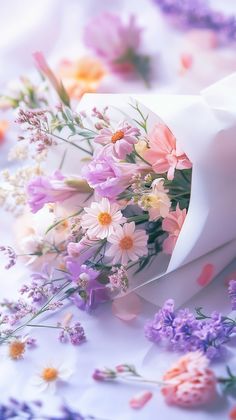 a bunch of flowers that are laying on a tablecloth with purple and white flowers