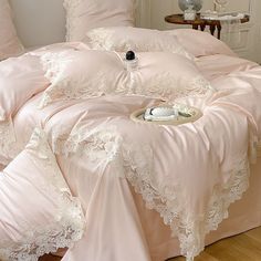 a bed with pink comforters and pillows on top of it, next to a lamp