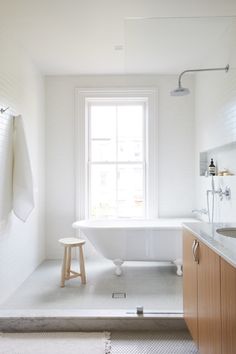 a bathroom with a white bathtub and wooden stool