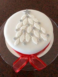 a cake decorated with white icing and a red ribbon