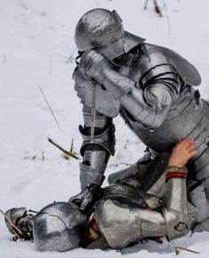 a man dressed in armor kneeling down in the snow