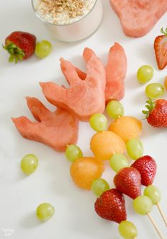 fruit skewers are arranged on a white surface