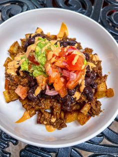 a white plate topped with black beans, guacamole and tortilla chips