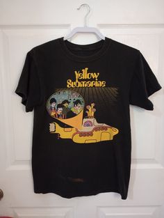 "This black 100% cotton short sleeve tee shirt by the beetle's company is a small size.  It has an image of the beetles in a yellow submarine. It is used, faded but still strong colors. It does have Clorox stain in front of shirt. Measurements flat across: shoulder-17 1/2 \" breast-19 1/2\" hip 19\" Length lower shoulder to bottom-22\". In close up, photo shows a gray color. But it is black. Unknown year. Can't see the mark on label." Mink Faux Fur Coat, Brown Wool Coat, Black Tee Shirt, Fur Coat Vintage, Orange Jacket, Winter Jeans, Yellow Submarine, Blue Tee, Strong Colors